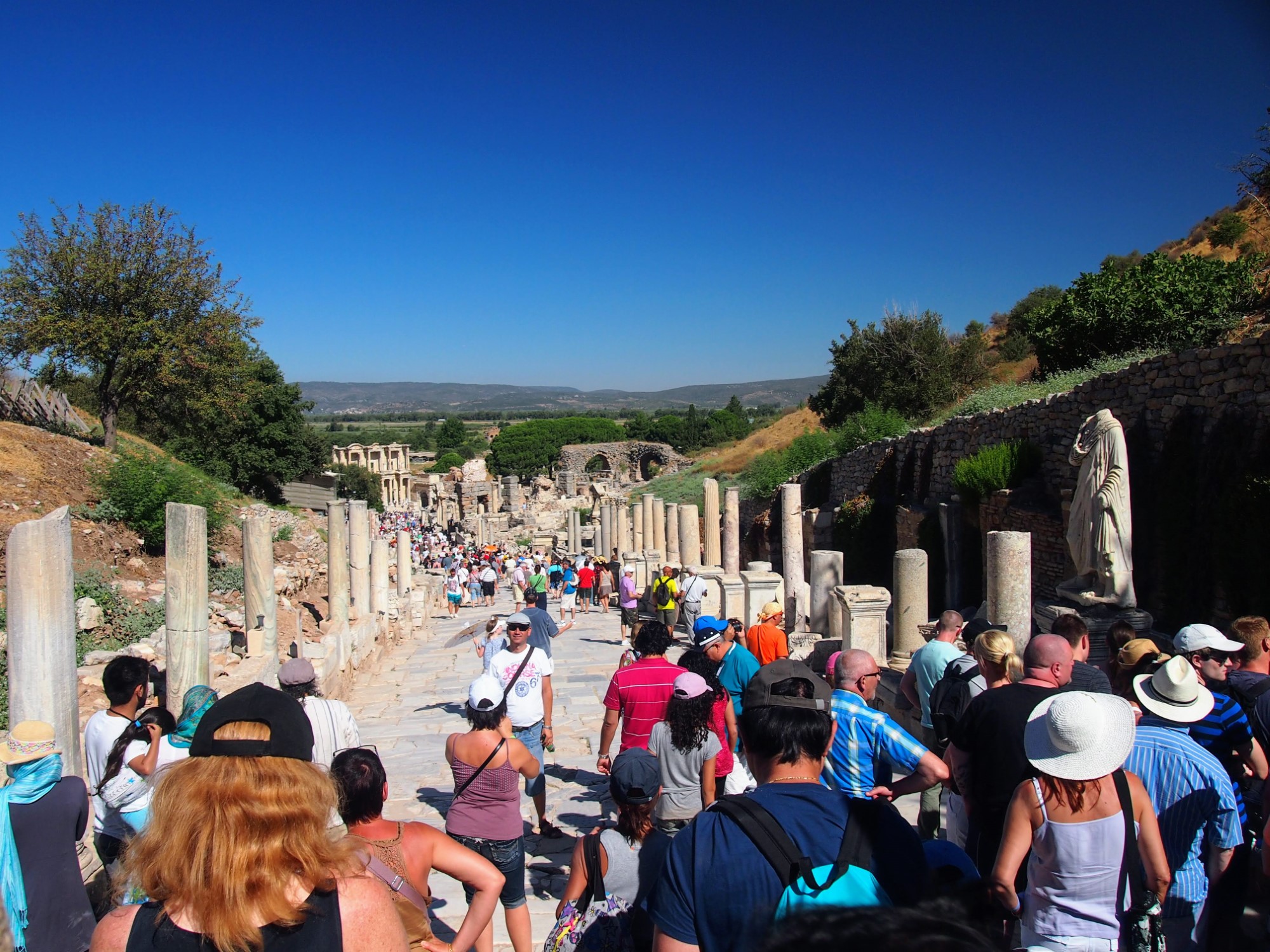 Crowds of people at Ephesus, at the top of a long descending path with the Library of Celsus visible at th ebottom