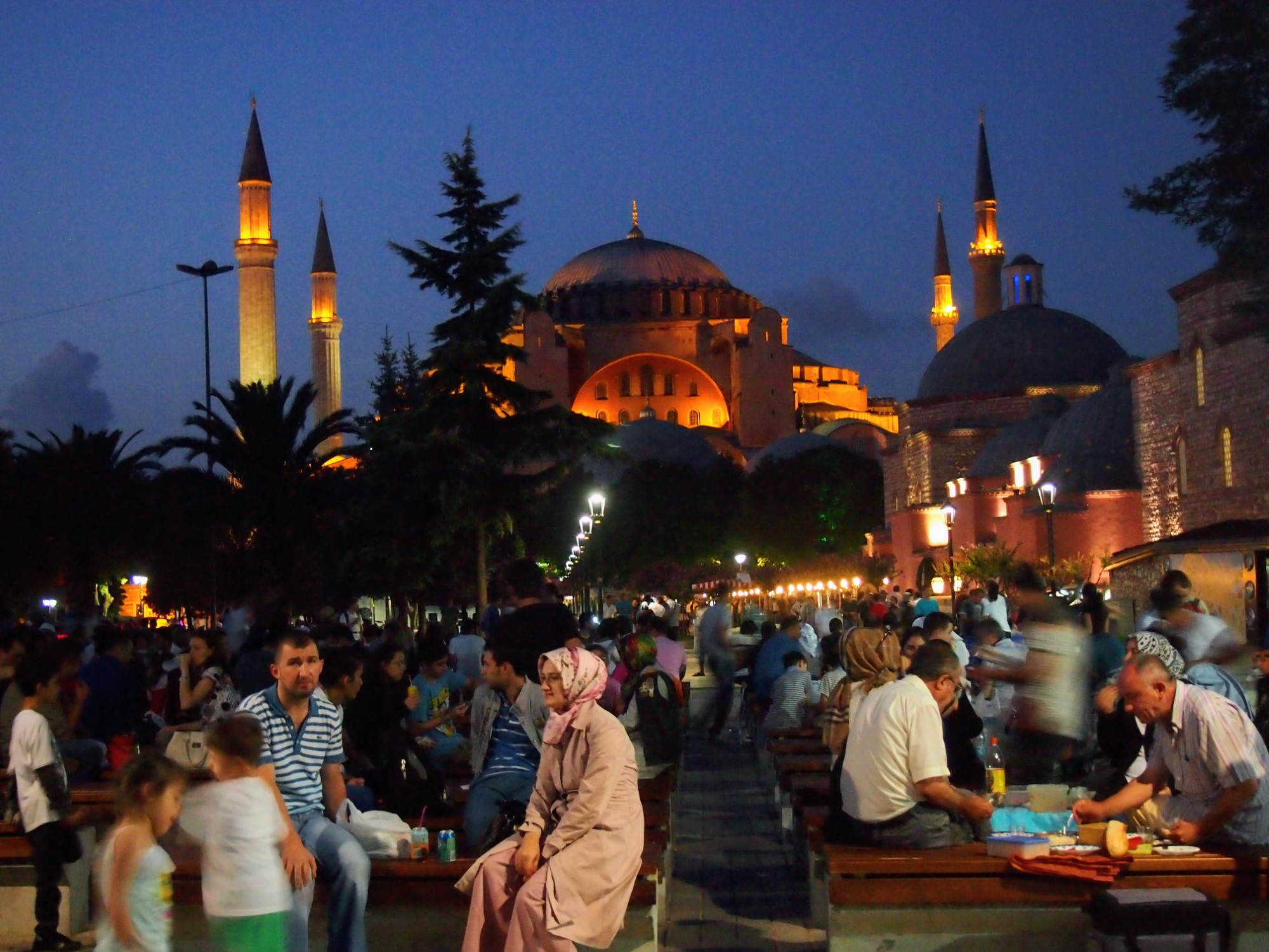 Many people sitting at dusk outside the Hagia Sophia in Istanbul