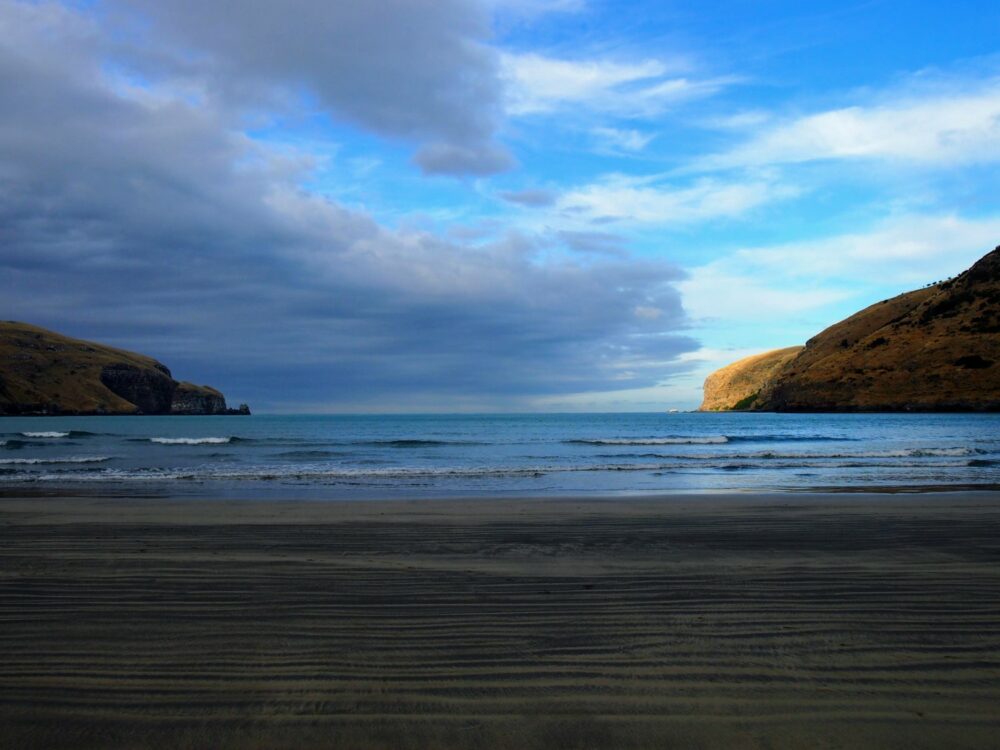 Beach on Banks Peninsula towards the end of the day, with clouds and blue sky