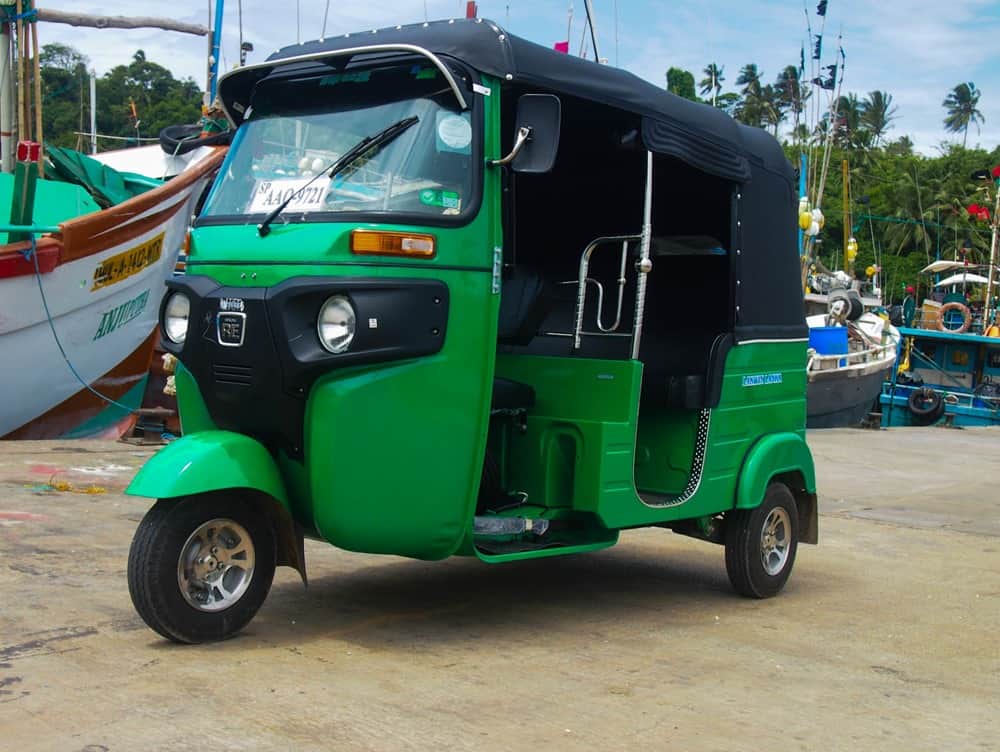 Tuk-tuk at a small marina with boats in the background