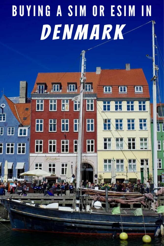 Text "Buying a SIM or eSIM in Denmark" overlaid on a photo of a boat tied up in front of some attractive colored buildings in Copenhagen. People are sitting at tables outside the buildings