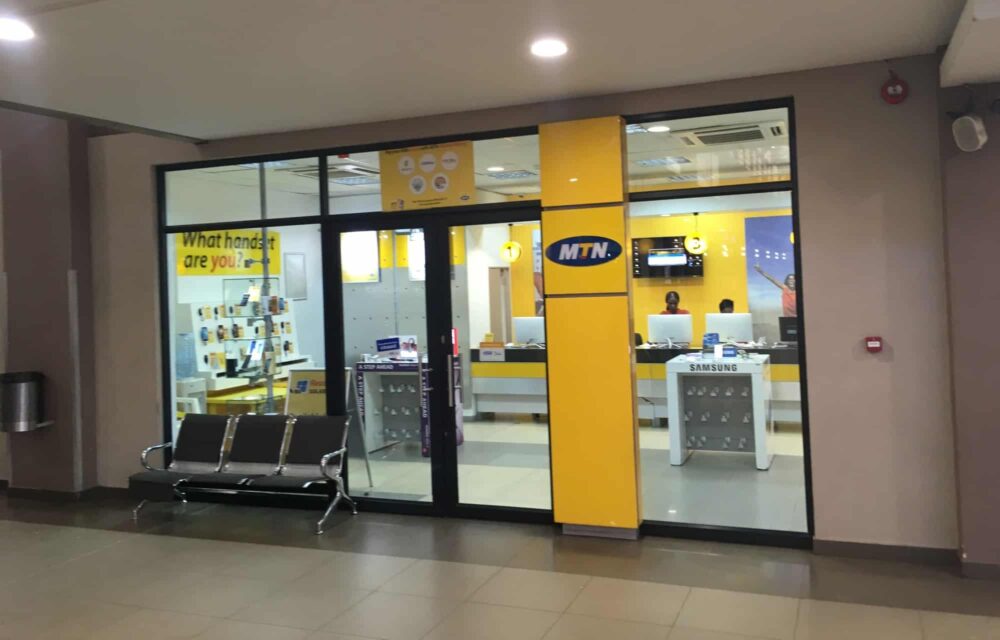 Outside view of an MTN store in Lusaka, with staff members visible through the windows behind a counter at the rear.