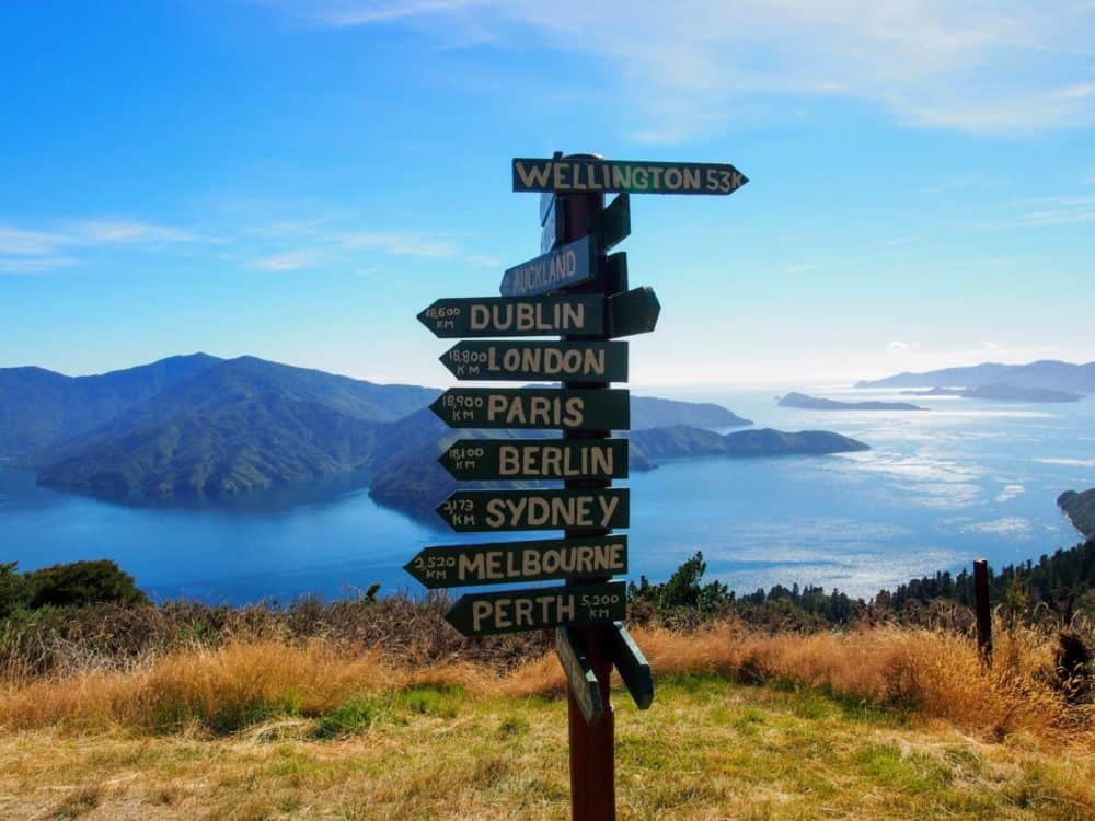 Signposts pointing to cities around the world, at Eatwell's Lookout on the Queen Charlotte Track in New Zealand
