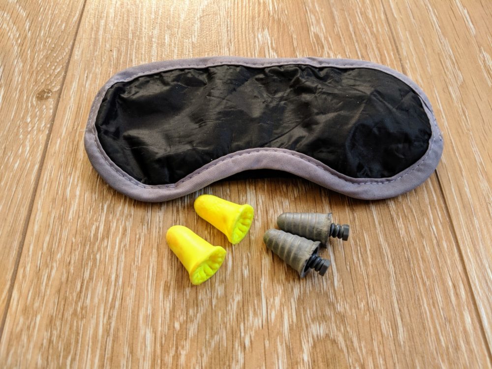 Two sets of earplugs and an  eye mask on a wooden floor.