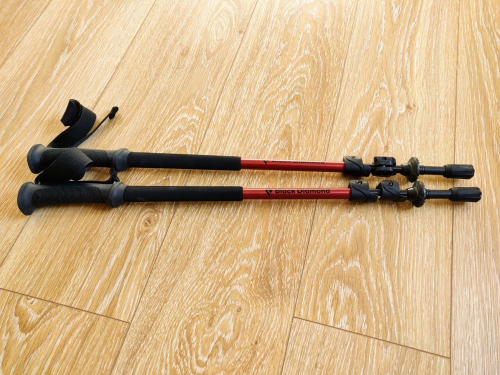 Two hiking poles beside each other on a wooden floor.