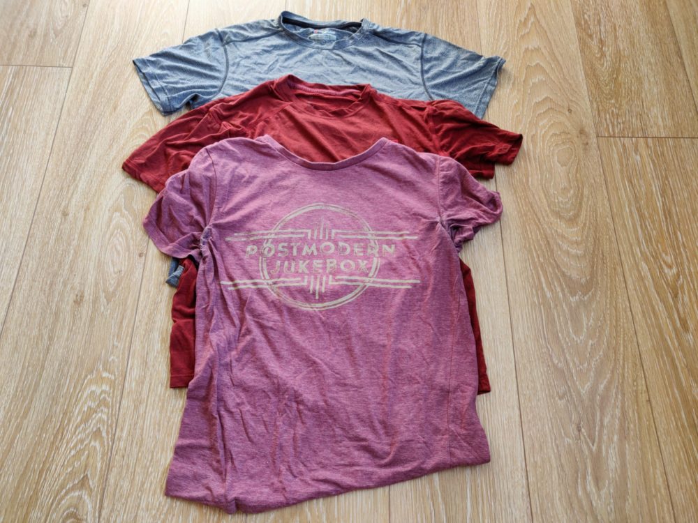 Three t-shirts on a wooden floor.