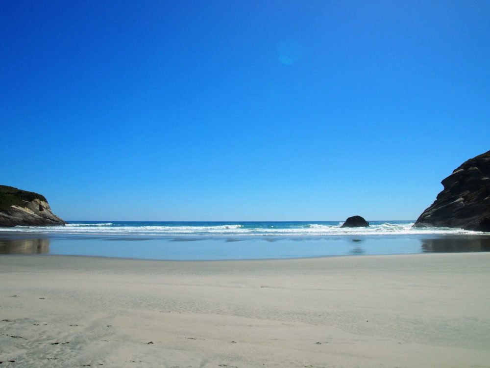 Wharariki beach view of sand, ocean, and large rocks