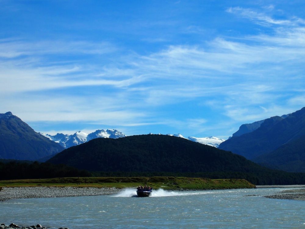 Jetboat on a river in New Zealand with mountains in the background