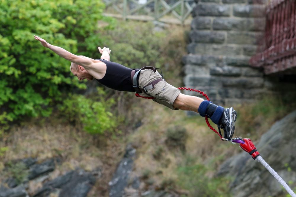 Man bungee-jumping off a bridge with arms outstretched