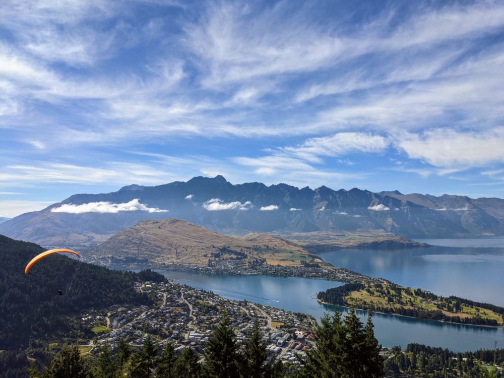 Person paragliding over Queenstown, New Zealand, with lake and mountains in background
