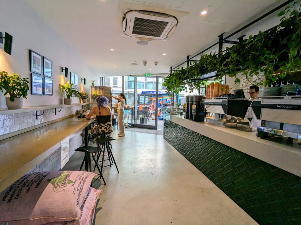 Inside view of Notting Hill Coffee Project, with coffee sacks in foreground and coffee equipment on counter on the right.