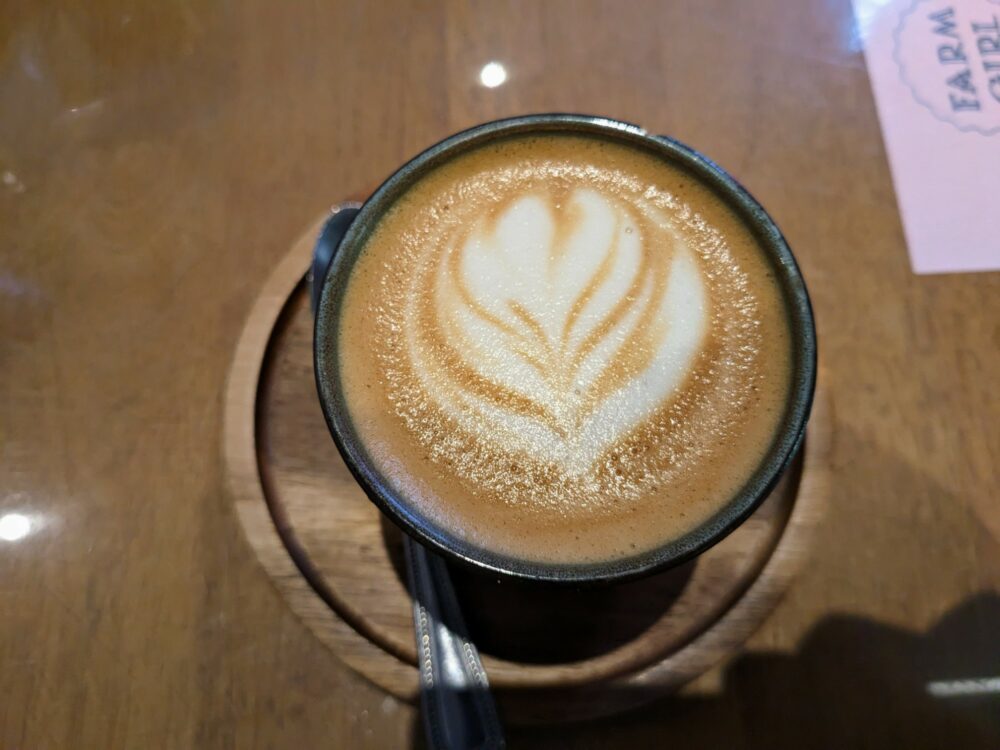 Overhead view of coffee with latte art at Farm Girl in Notting Hill, with small section of menu visible on right