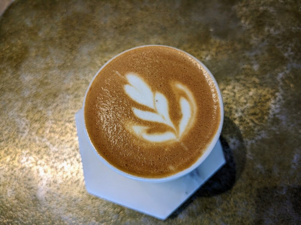 Overhead view of coffee with latte art on a metal table