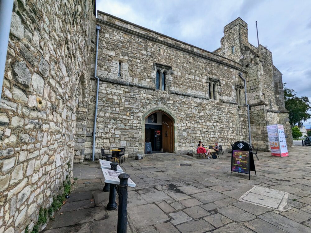 The outside of God's House Tower in Southampton, an old brick building with information boards and a couple of tables and chairs outside.