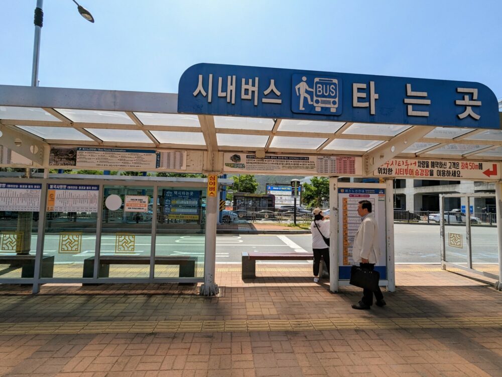 Bus stop at KTX train station in Singyeongju, South Korea, with timetables for different routes.