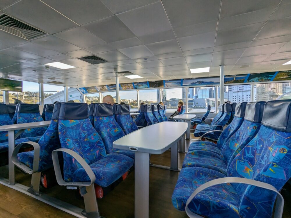 Inside a ferry, with many seats visible and a few passengers