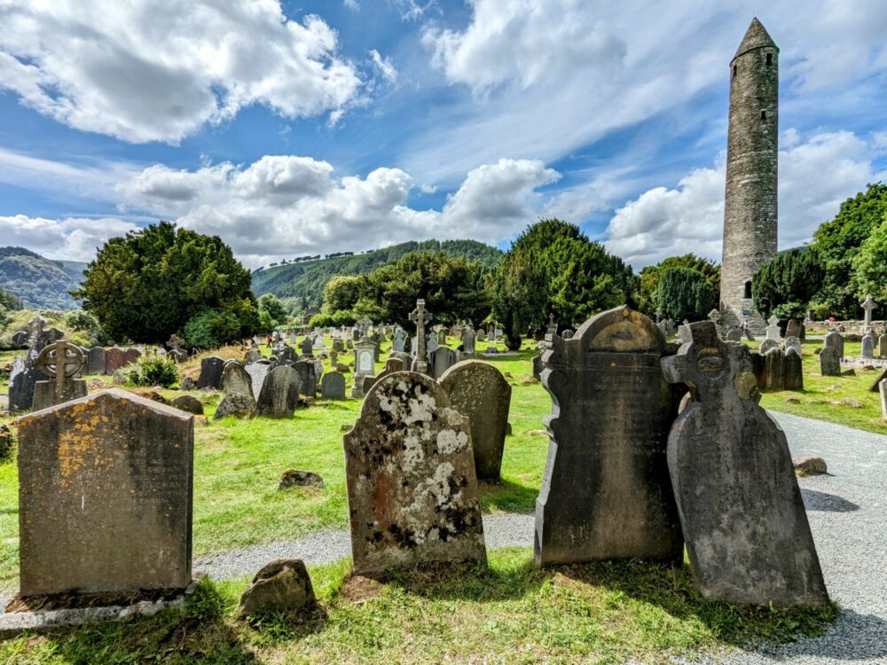 Rows of old gravestones with paths alongside, and a tall round tower in the middle distance