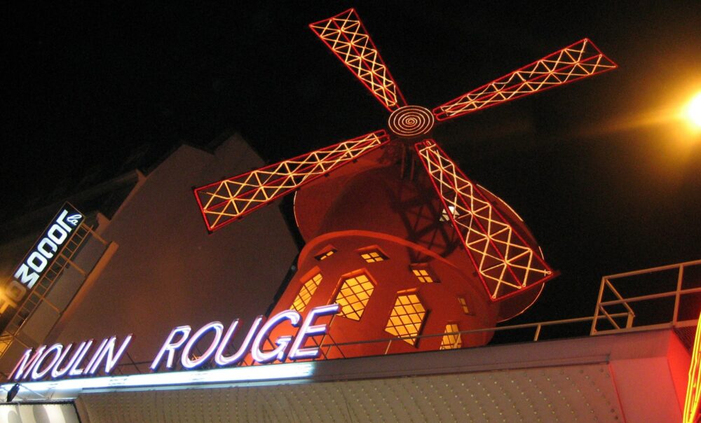Red windmill on a building with a sign underneath saying Moulin Rouge