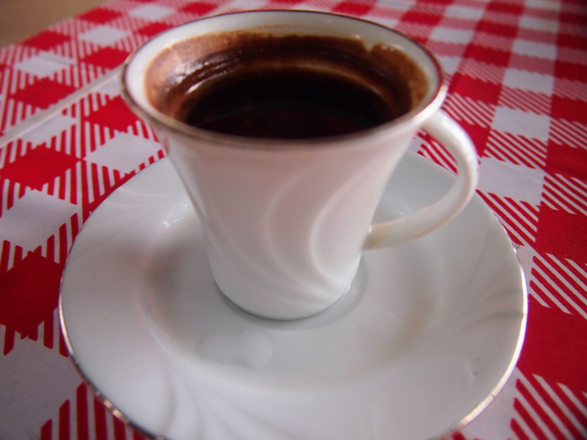 Small cup of Turkish coffee on a red checked tablecloth